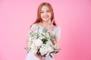 Genç Asyalı gelin pembe arka planda poz veriyor