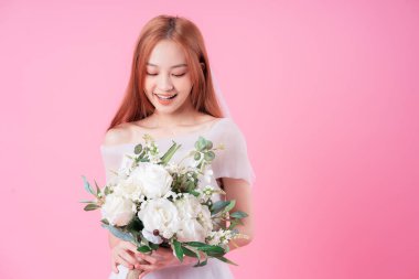 Genç Asyalı gelin pembe arka planda poz veriyor