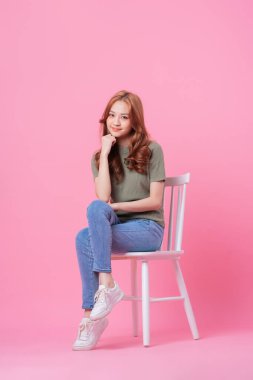 Genç Asyalı kadın pembe arka planda akıllı telefon kullanıyor.