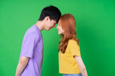 Genç Asyalı çift yeşil arka planda poz veriyor