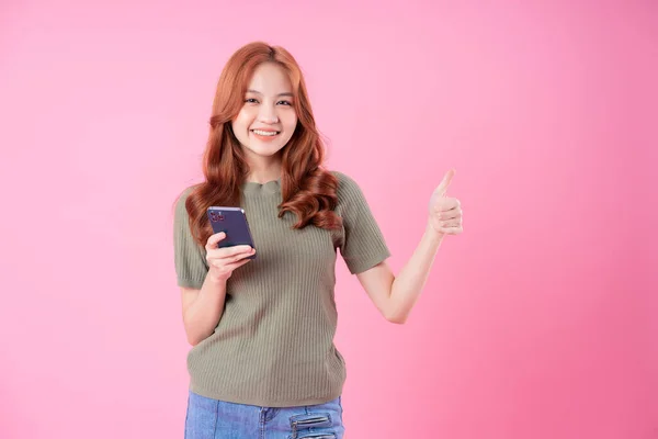 분홍색 배경으로 스마트폰을 사용하는 아시아의 — 스톡 사진