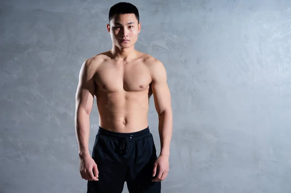 灰色の背景にポーズ筋肉アジアの男 — ストック写真