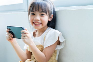 Evde akıllı telefon kullanan Asyalı çocuk