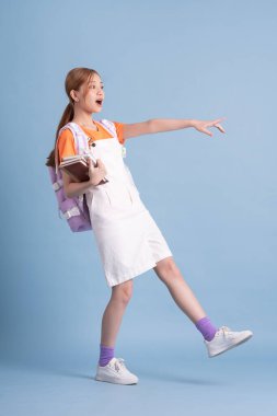 Genç Asyalı öğrenci mavi arka planda poz veriyor