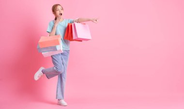 Genç Asyalı kadın pembe arka planda alışveriş çantası tutuyor.