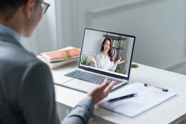 Asyalı erkek müdür adaylarla video görüşmesi yapıyor.
