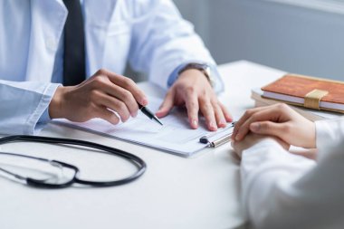Asyalı erkek doktor klinikteki hastayı muayene ediyor.