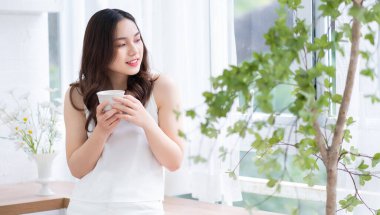 Güzel bir Asyalı kadının sabah evde çay içişi.