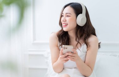 Evde sabahları müzik dinleyen Asyalı genç bir kadın resmi