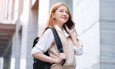 Genç Asyalı kadın sokakta akıllı telefon kullanıyor.