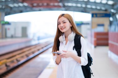 Genç Asyalı kız istasyonda treni bekliyor.