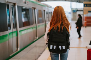 Genç Asyalı kız istasyonda treni bekliyor.