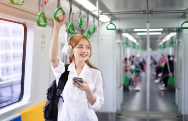 Metroda akıllı telefon kullanan Asyalı genç bir kadının görüntüsü