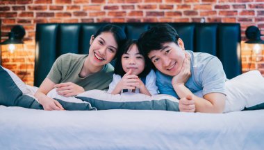 Genç Asyalı aile yatakta.