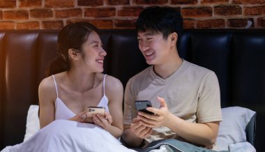 Genç Asyalı çift gece akıllı telefon kullanıyor.