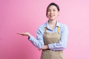 Genç Asyalı garson pembe arka planda duruyor.