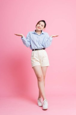 Pembe arka planda poz veren Asyalı genç bir kızın portresi