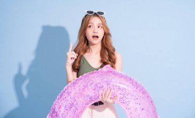 Mavi arka planda yüzen Asyalı genç bir kız resmi, yaz tatili konsepti.