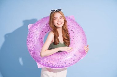 Mavi arka planda yüzen Asyalı genç bir kız resmi, yaz tatili konsepti.