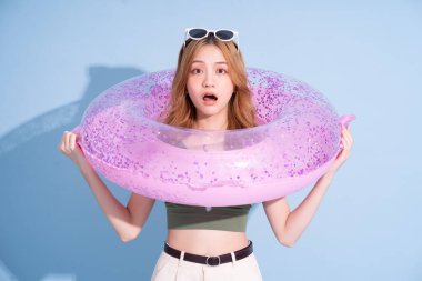 Mavi arka planda yüzen Asyalı genç bir kız resmi, yaz tatili konsepti.