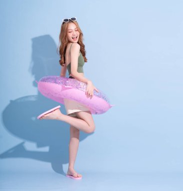 Mavi arka planda yüzen Asyalı genç bir kız resmi, yaz tatili konsepti.