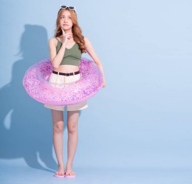 Mavi arka planda yüzen Asyalı genç bir kız resmi, yaz tatili konsepti.