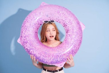 Mavi arka planda yüzen Asyalı genç bir kız resmi, yaz tatili konsepti.