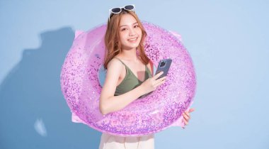 Mavi arka planda yüzen Asyalı genç bir kız resmi, yaz tatili konsepti.