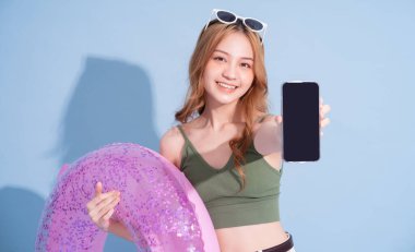 Mavi arka planda yüzen Asyalı genç bir kız resmi, yaz tatili konsepti.