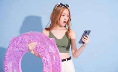 Mavi arka planda yüzen Asyalı genç bir kız resmi, yaz tatili konsepti.