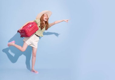 Mavi arka planda bavulu olan Asyalı genç bir kız resmi, seyahat konsepti.