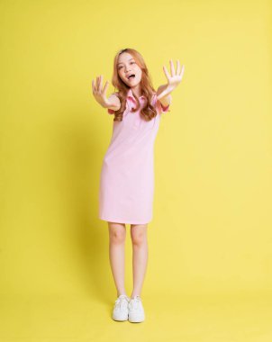 Sarı arka planda duran Asyalı genç kızın tam boy görüntüsü