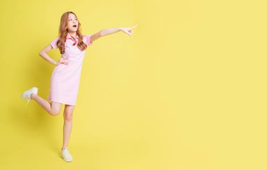 Sarı arka planda duran Asyalı genç kızın tam boy görüntüsü