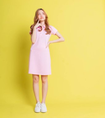 Sarı arka planda duran Asyalı genç kızın tam boy görüntüsü