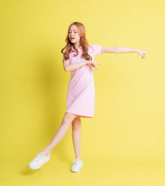 Sarı arka planda duran Asyalı genç kızın tam boy görüntüsü