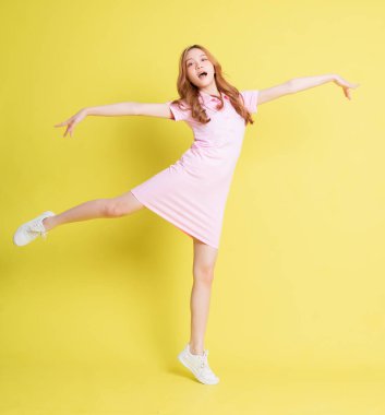 Sarı arka planda duran Asyalı genç kızın tam boy görüntüsü