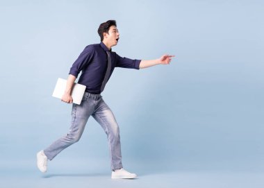 Full length image of young Asian businessman on blue background