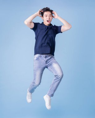 Full length image of young Asian man posing on blue background