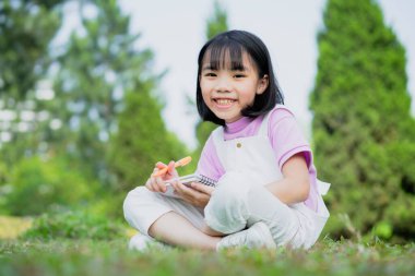 Parkta okuyan Asyalı küçük bir kız resmi