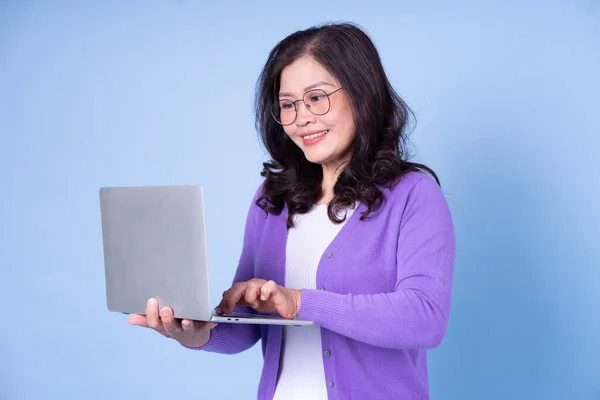 Portrait Middle Aged Asian Woman Using Laptop Blue Background — Fotografia de Stock