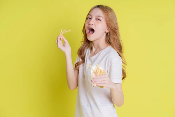 Image Young Asian Girl Eating French Fries Yellow Background — стокове фото