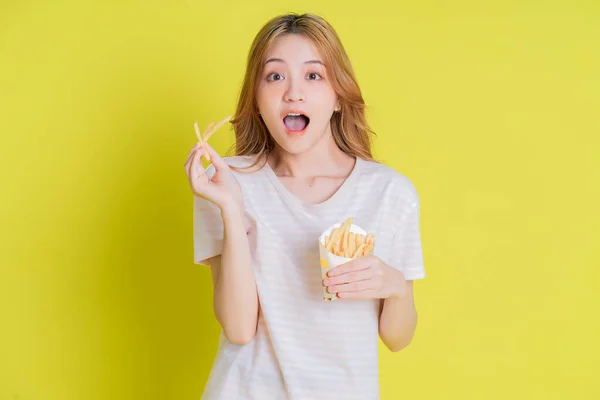 Image Young Asian Girl Eating French Fries Yellow Background — стокове фото