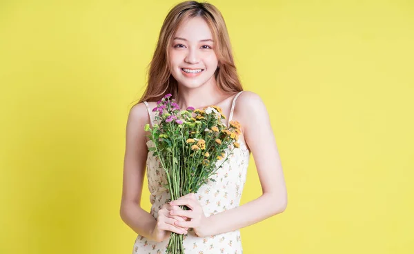 Image Young Asian Woman Holding Flowers Yellow Background — стокове фото