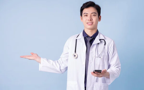 蓝色背景的年轻亚洲男医生画像 — 图库照片