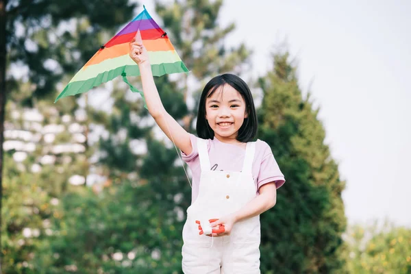 Parkta uçurtma oynayan Asyalı küçük bir kız resmi