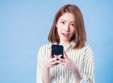 Mavi arka planda akıllı telefon kullanan Asyalı genç bir kız görüntüsü
