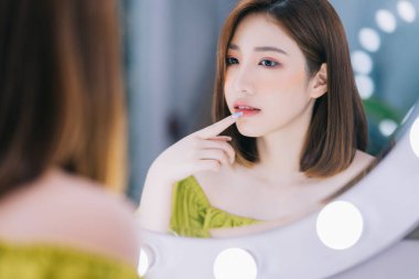 Aynanın önünde duran Asyalı genç bir kız.