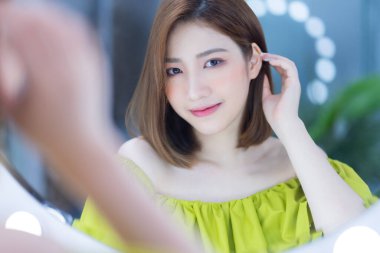 Aynanın önünde duran Asyalı genç bir kız.