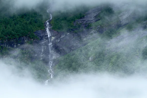 Cascata che sorge nella nebbia in un fiordo norvegese, Norvegia . — Foto Stock