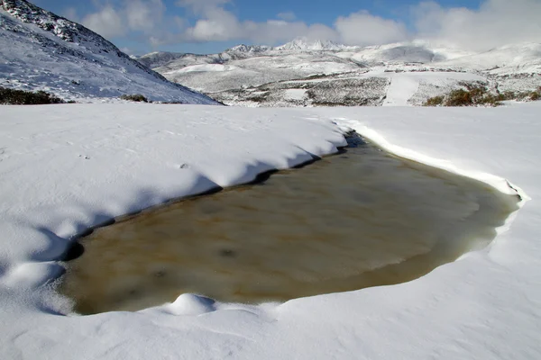 Bruin lake in het midden van de sneeuw in asturias, Spanje. — Stockfoto